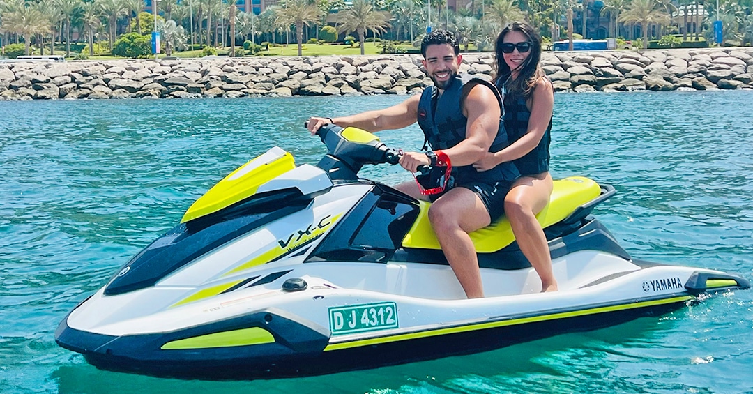 Couple posed for in front of Atlantis Hotel while riding Jet Ski